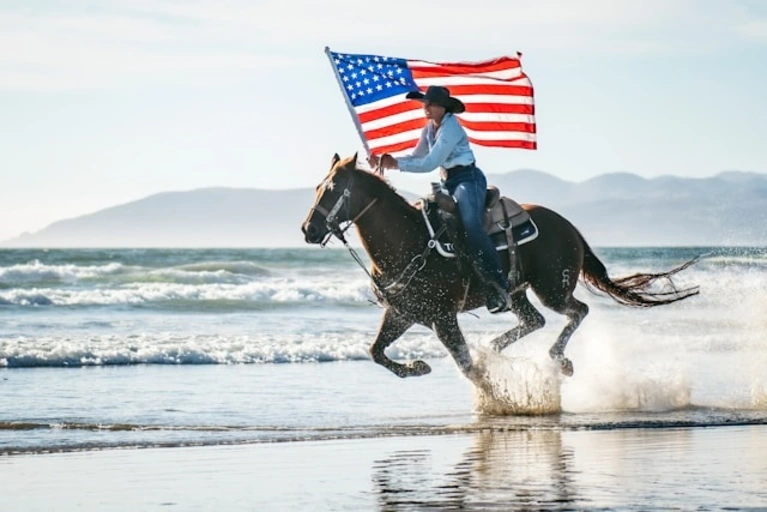 Am Strand galoppierende Frau mit US-Flagge